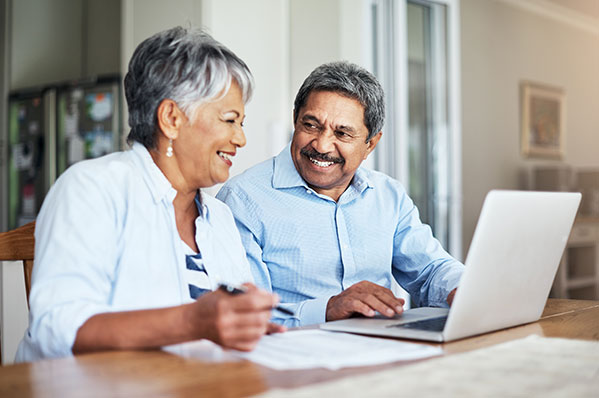 older couple sitting at a table with a laptop