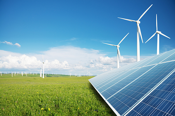 modern windmills and solar panels against green grass and a blue sky