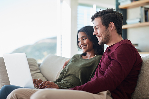 young couple sitting on their sofa looking at the laptop