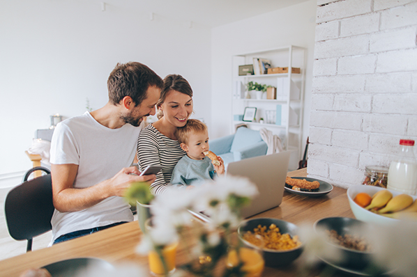 young family having lunch at the kitchen table with a young boy on his mom's lap