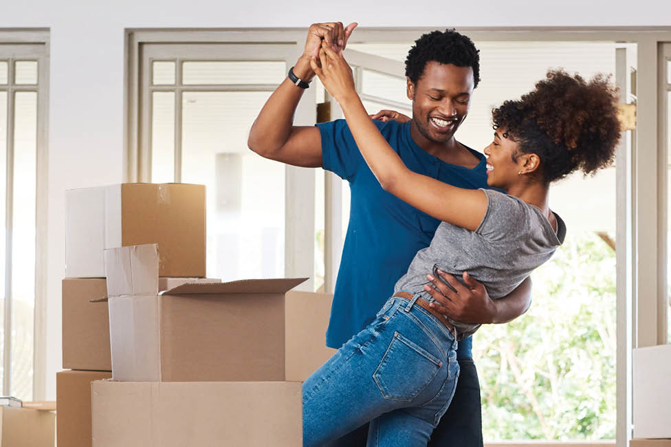 young couple dancing among packing boxes in their new home