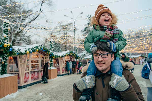 small child on dad's shoulders bundled up walking around outside in cold weather