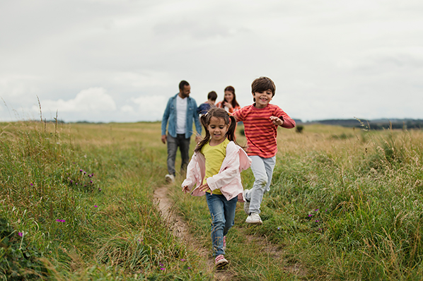 young family out for a walk in the field with two young children running ahead