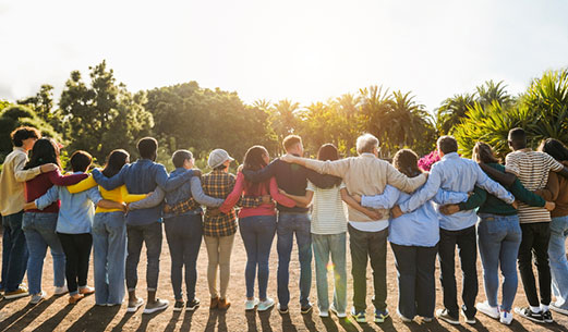 a group of people standing away from the camera all hugging in a row