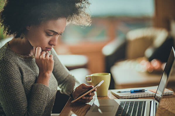 young woman with a confused expression looking at her phone