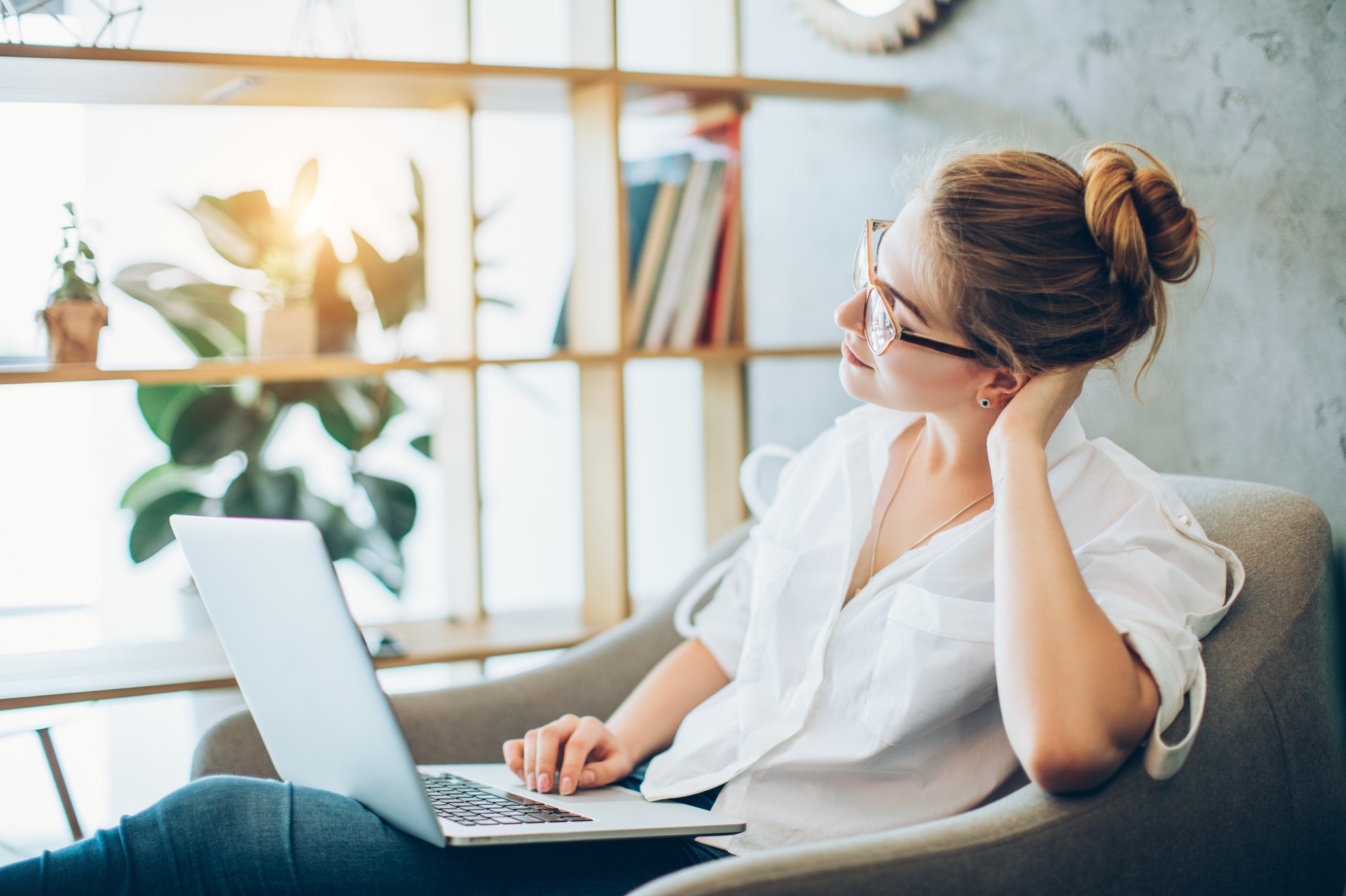 young woman sitting in her armchair with a laptop