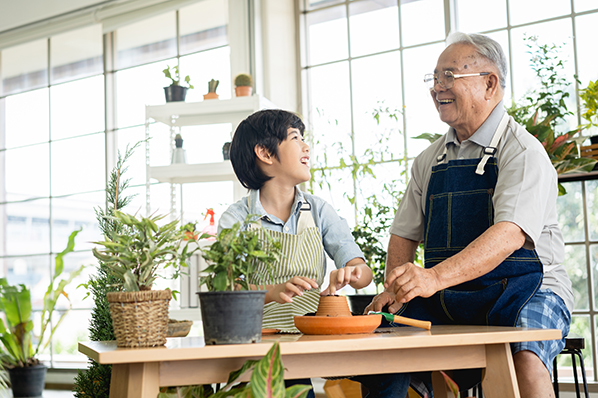 Older male with young grandson laughing while re-potting house plants.