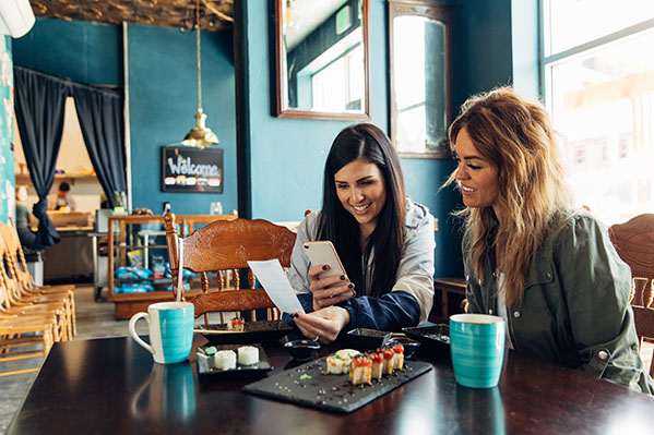 two women smiling and eating sushi