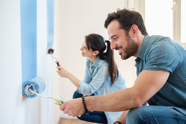 a couple painting a house wall blue