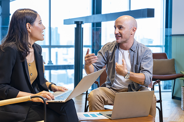 man and woman sitting with laptops