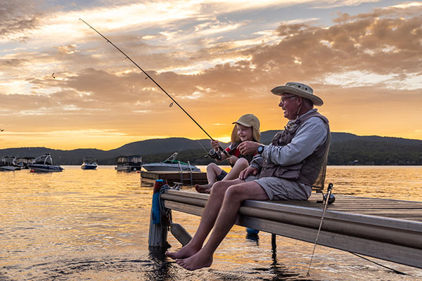 grandpa and grandson sitting on the lake dock fishing