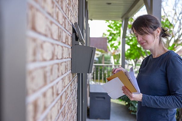 woman looking through the mail she just picked up from her mailbox