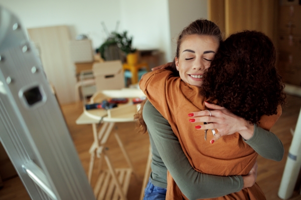 two young women hugging in their new home