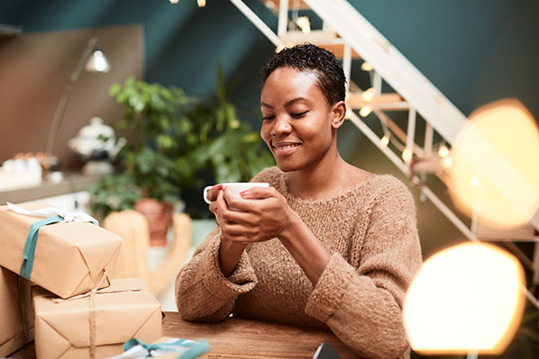 young woman taking a break from wrapping presents and enjoying a cup of tea