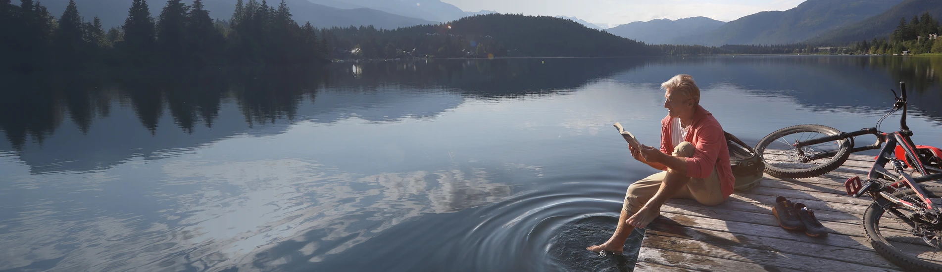 Man on dock on a lake reading a book