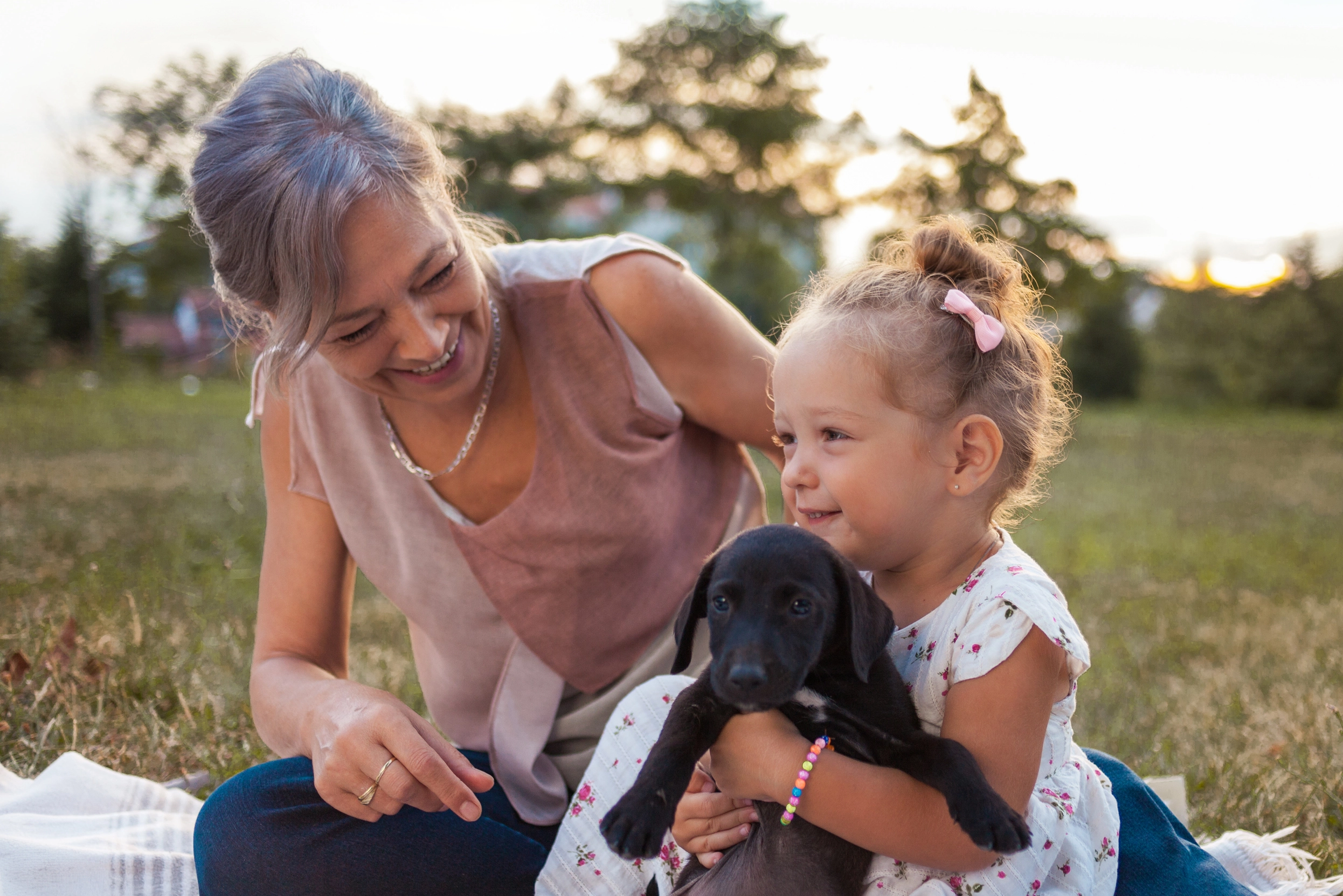 A woman and a child hugging a puppy