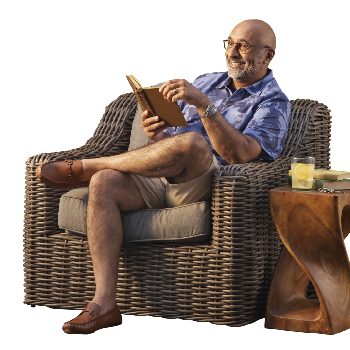 older well to do man smiling sitting on his resort home patio