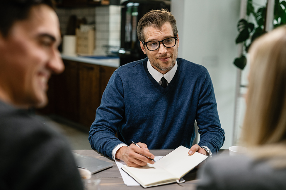 An male advisor speaking to a man and woman in an office