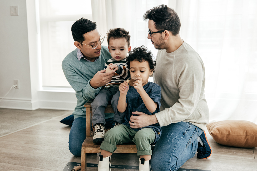two young fathers playing with their toddler sons 