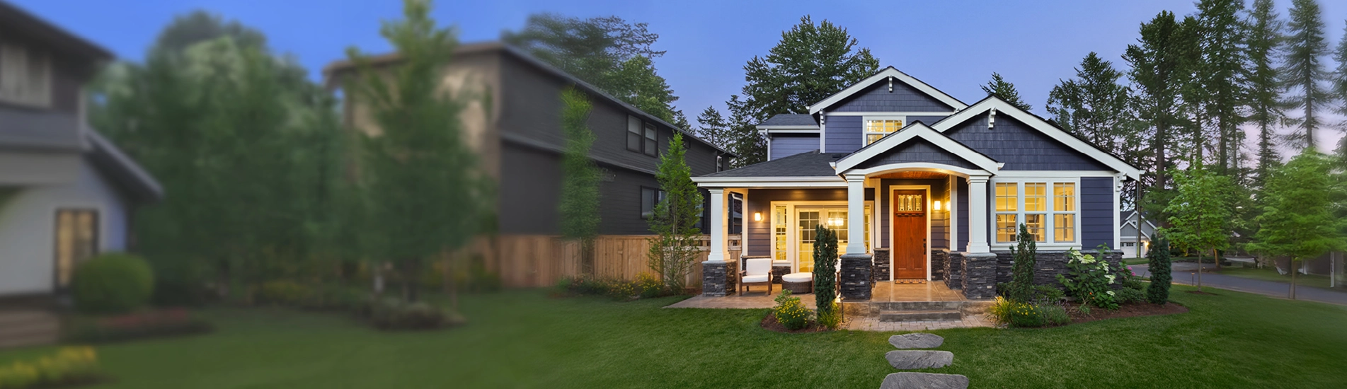 A house in the suburbs with lights on at dusk