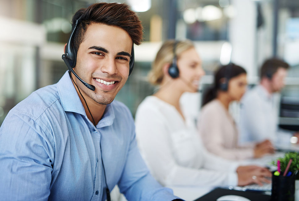 friendly young male customer service advisor wearing a headset smiling at the camera