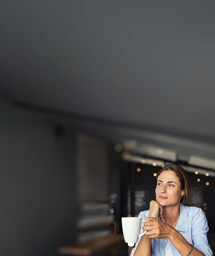 A woman holding a coffee mug and staring out the window