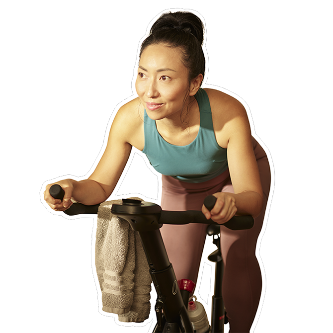 middle-aged Asian woman riding her stationary exercise bike