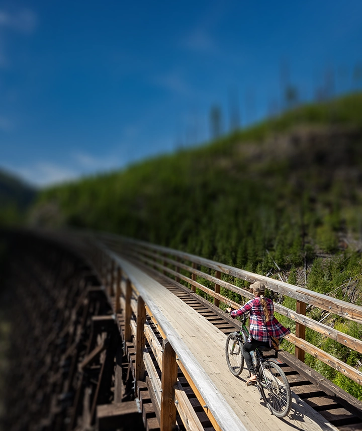 mom and daughter riding their bikes across an old truss bridge