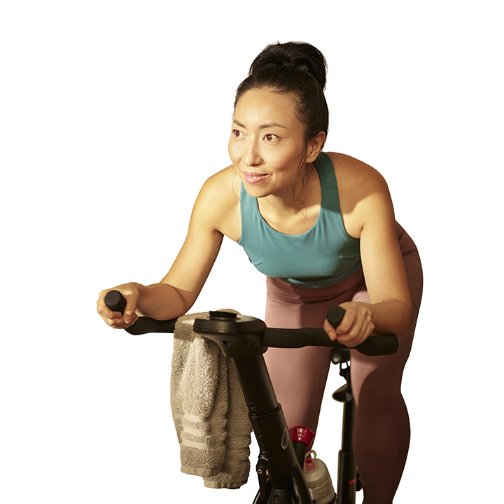 middle-aged Asian woman riding her stationary exercise bike