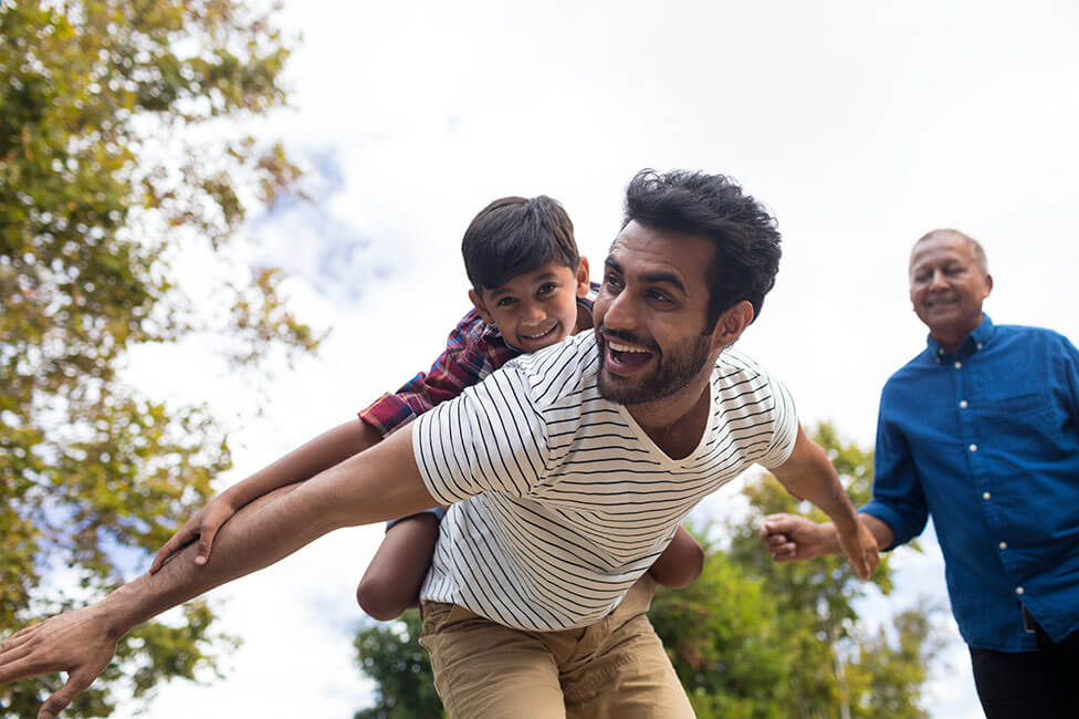 young boy on his dad's shoulders pretending to be an airplane