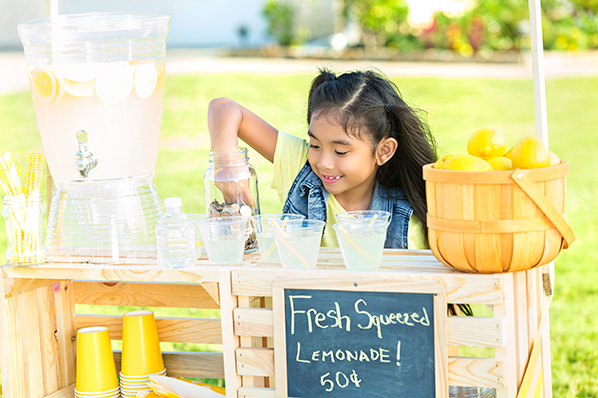 young girl counting her money at a lemonade stand