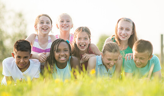 8 kids laying down in the grass smiling at the camera