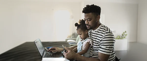 dad doing online banking with daughter sitting on his lap