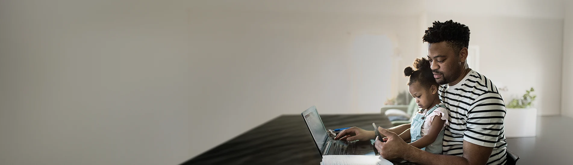 dad doing online banking with daughter sitting on his lap