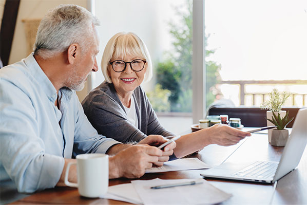 senior couple looking at their finances at home on their laptop