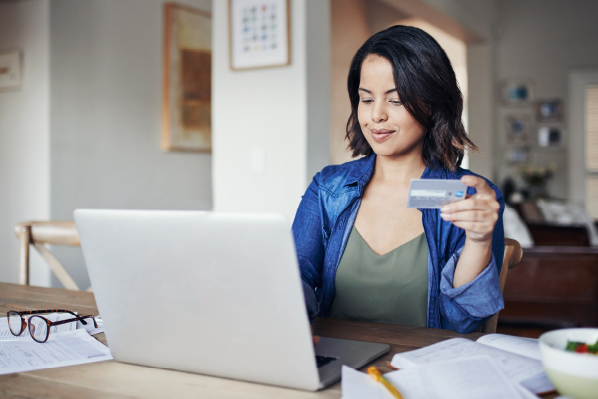 woman with a laptop holding a debit card